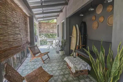 a room with a porch with a surfboard and chairs at La Canasta in El Zonte