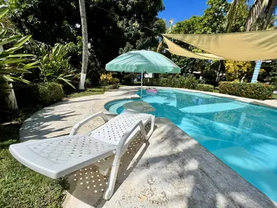 a chair and an umbrella next to a swimming pool at Beautiful beach house in Los Cobanos El Salvador in Los Cóbanos