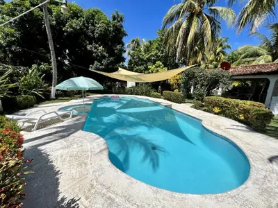 a swimming pool in a yard with an umbrella at Beautiful beach house in Los Cobanos El Salvador in Los Cóbanos