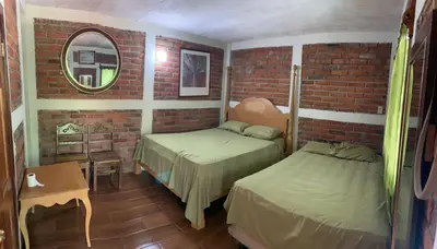 a bedroom with two beds and a brick wall at Green Canyon in El Jurón