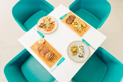 a table with plates of food on it with blue chairs at Equinoccio Hotel in Santa Ana