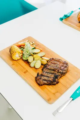 a wooden cutting board with steak and vegetables on it at Equinoccio Hotel in Santa Ana