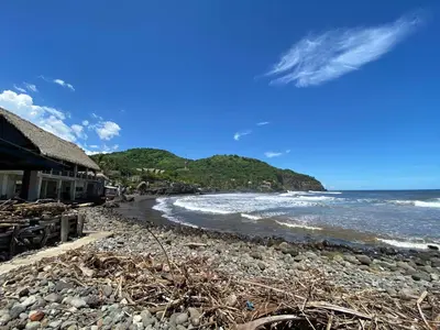 a rocky beach with a building and the ocean at Lote 44 Guesthouse in El Zonte