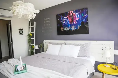 a bedroom with a white bed and a painting on the wall at Avitat Joy 2Brm Amazing City&Volcano View Pool&Gym in San Salvador
