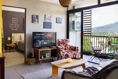 a living room with a couch and a tv and a balcony at Avitat Joy 2Brm Amazing City&Volcano View Pool&Gym in San Salvador
