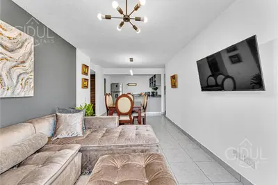 a living room with a couch and a dining room at Cozy, Modern and Centric Apartment with pool and gym in San Salvador