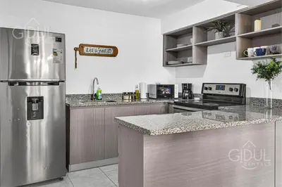 a kitchen with a stainless steel refrigerator and cabinets at Cozy, Modern and Centric Apartment with pool and gym in San Salvador