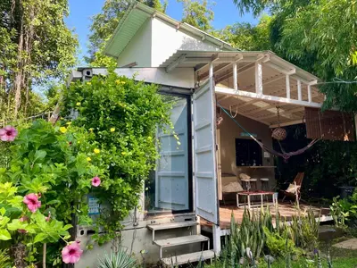 a tiny house with a greenhouse and flowers at Wabi Sabi , casa de playa in Tamanique
