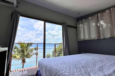a bedroom with a large window with a view of the ocean at Quinta Sunrise, Lago de Coatepeque in El Congo