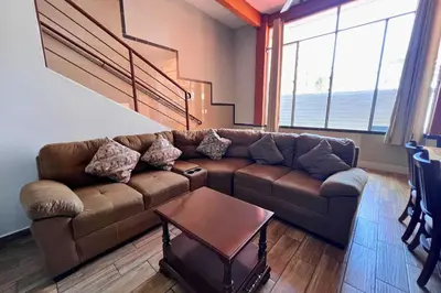 a living room with a brown couch and a table at Quinta Sunrise, Lago de Coatepeque in El Congo