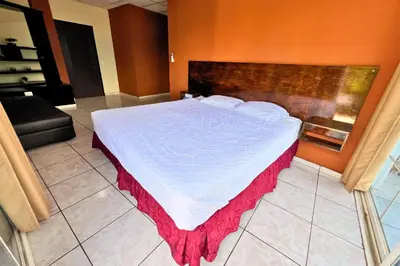 a bedroom with a large bed with a red blanket on it at Rancho Chanel, Lago de Coatepeque in El Congo