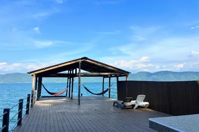 a pier with a swing and a hammock on the water at Rancho Chanel, Lago de Coatepeque in El Congo