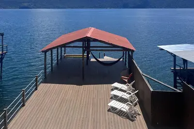 a dock with a hammock on top of the water at Rancho Chanel, Lago de Coatepeque in El Congo