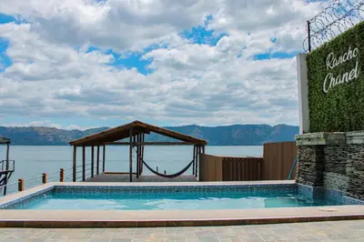 a swimming pool with a gazebo next to the water at Rancho Chanel, Lago de Coatepeque in El Congo