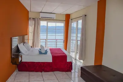 a bedroom with a bed and a large window at Rancho Chanel, Lago de Coatepeque in El Congo