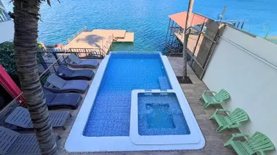 a swimming pool on a deck with chairs and the ocean at Quinta Sunset, Lago de Coatepeque in El Congo