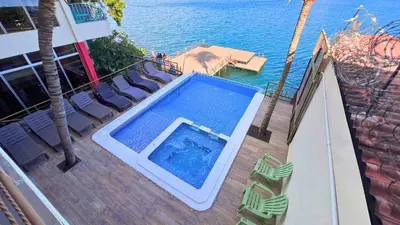 a swimming pool on a deck with chairs and the ocean at Quinta Sunset, Lago de Coatepeque in El Congo