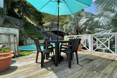 a black table and chairs with an umbrella on a deck at Treehouse in Tamanique