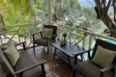 a porch with chairs and a table on a deck at Treehouse in Tamanique
