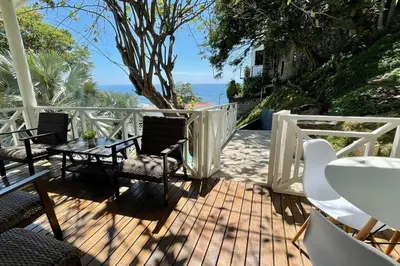 a patio with a table and chairs and the ocean at Treehouse in Tamanique