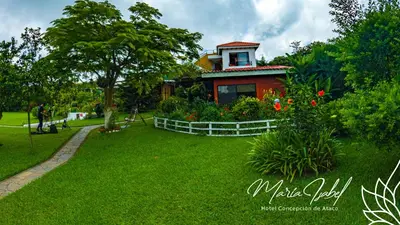 a house in a park with a green yard at Hotel María Isabel Ataco in Concepción de Ataco