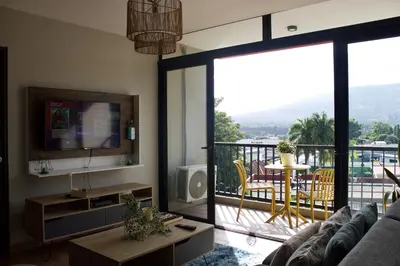 a living room with a television and a balcony at Avitat Joy City &Volcano View 2Brm Pool &Gym in San Salvador
