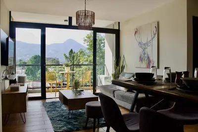 a living room with a table and a large window at Avitat Joy City &Volcano View 2Brm Pool &Gym in San Salvador
