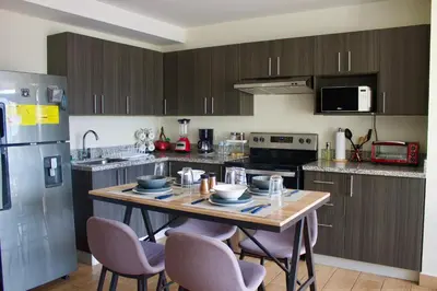 a kitchen with a table with chairs and a refrigerator at Avitat Joy City &Volcano View 2Brm Pool &Gym in San Salvador