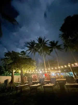 a group of tables and chairs at night with palm trees at LOOKING2GOOD in El Zonte