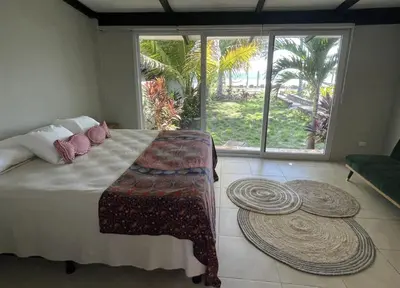 a bedroom with a large bed and a large window at LOOKING2GOOD in El Zonte