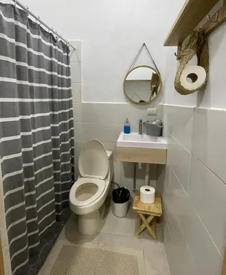 a bathroom with a toilet and a sink and a mirror at LOOKING2GOOD in El Zonte