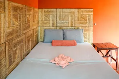 a bed with a pink flower on top of it at Casa Makoi in Tamanique