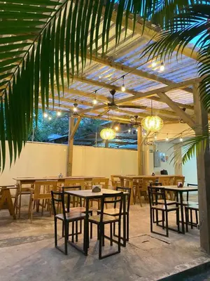 a restaurant with tables and chairs and a palm tree at Casa Makoi in Tamanique
