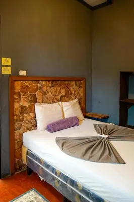 a bed in a room with a stone wall at Casa Makoi in Tamanique