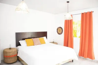 a bedroom with a white bed and orange curtains at Habitacion Fuego - Villa Valle Campo in Nahuizalco
