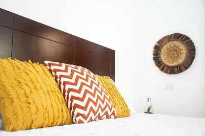 a bed with yellow and orange pillows on it at Habitacion Fuego - Villa Valle Campo in Nahuizalco