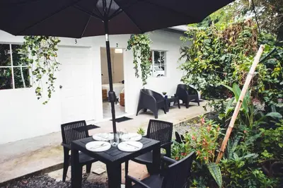 a black table with chairs and an umbrella at Habitacion Fuego - Villa Valle Campo in Nahuizalco