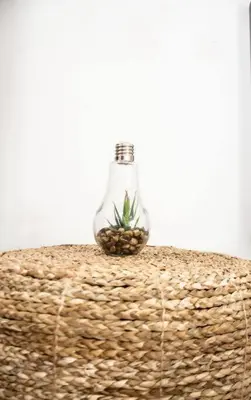a glass bottle with a plant in it sitting on a basket at Habitacion Fuego - Villa Valle Campo in Nahuizalco