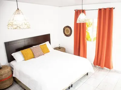 a bedroom with a bed with orange curtains and a window at Habitacion Fuego - Villa Valle Campo in Nahuizalco