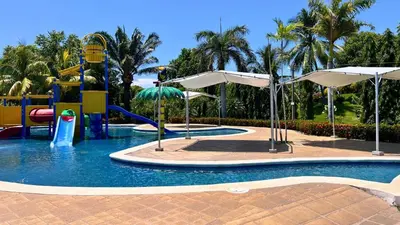 a pool with a water park with slides and umbrellas at Quinta Luna Mar, Residencial Las Veraneras in Acajutla