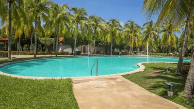 a swimming pool with palm trees in a resort at Quinta Luna Mar, Residencial Las Veraneras in Acajutla
