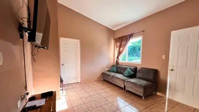 a living room with a couch and a window at Quinta Luna Mar, Residencial Las Veraneras in Acajutla
