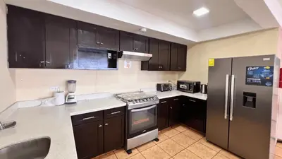 a kitchen with black cabinets and stainless steel appliances at Quinta del Carmen, Playa San Diego in La Libertad