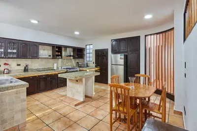a kitchen with wooden cabinets and a table and chairs at New in the heart of the city 5 min to US Embassy in Nuevo Cuscatlán