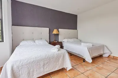 a bedroom with two beds with white sheets and a lamp at New in the heart of the city 5 min to US Embassy in Nuevo Cuscatlán