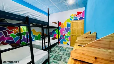 a room with two bunk beds and a colorful wall at Samay Hostel in Juayúa