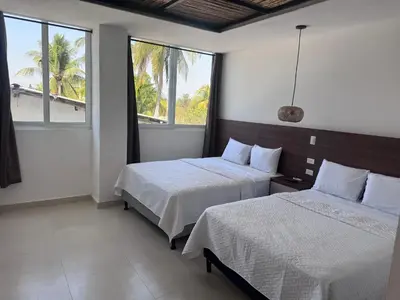 two beds in a room with two windows at Hotel Paseo del Sol in La Paz