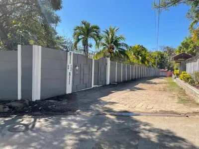 a white fence with palm trees on the side of a road at Beach On The Rocks in El Zonte