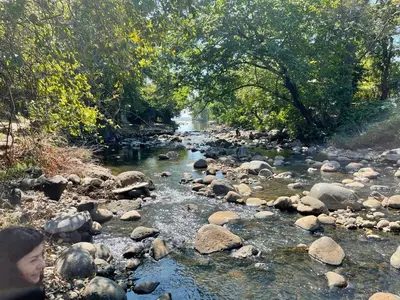 a river with rocks and a person standing next to it at Beach On The Rocks in El Zonte