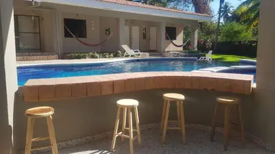 a swimming pool with stools in front of a house at Beach On The Rocks in El Zonte